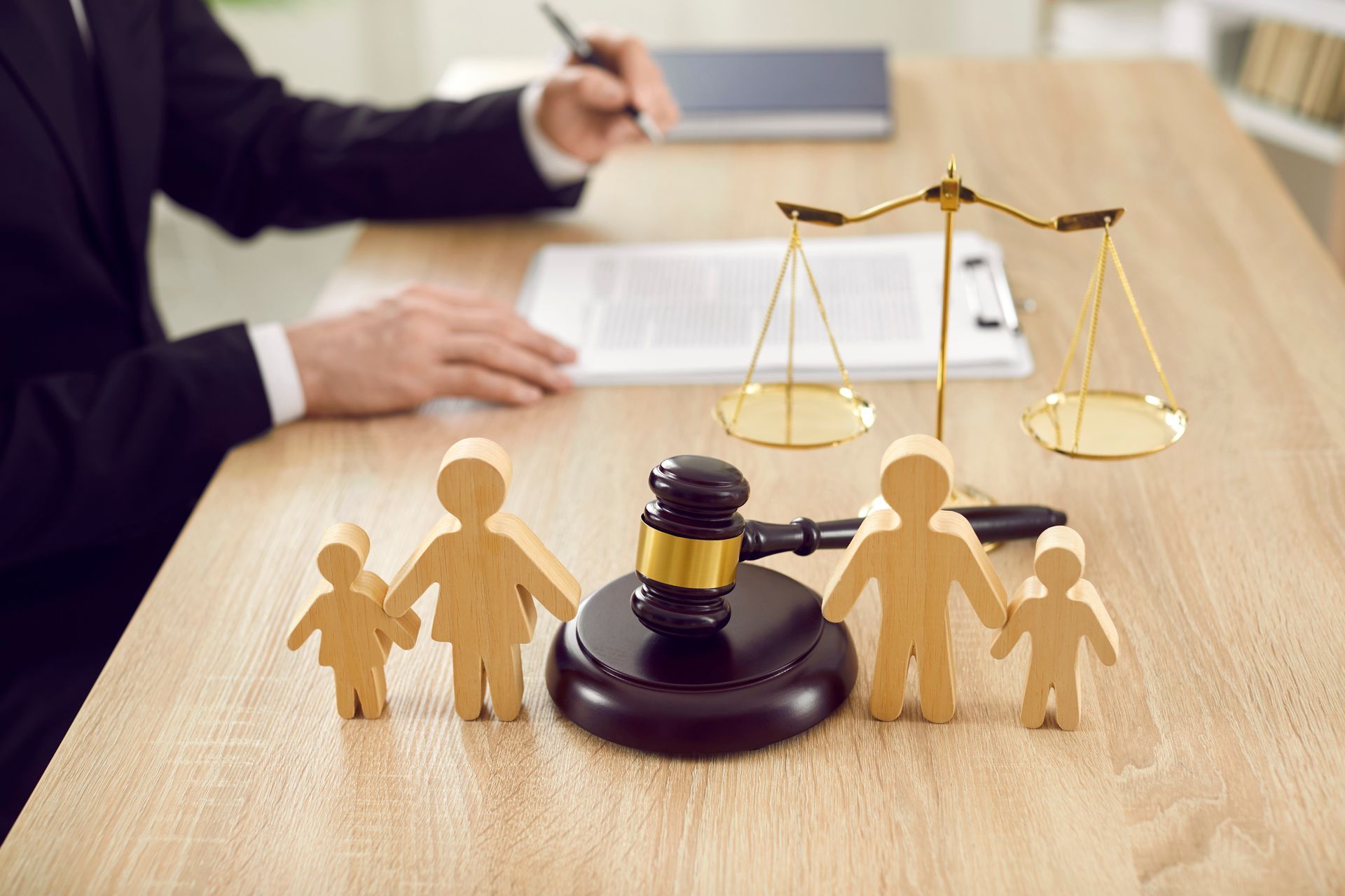 Homme, assis à un bureau sur lequel sont posées des figurines d'une famille et un marteau de justice
