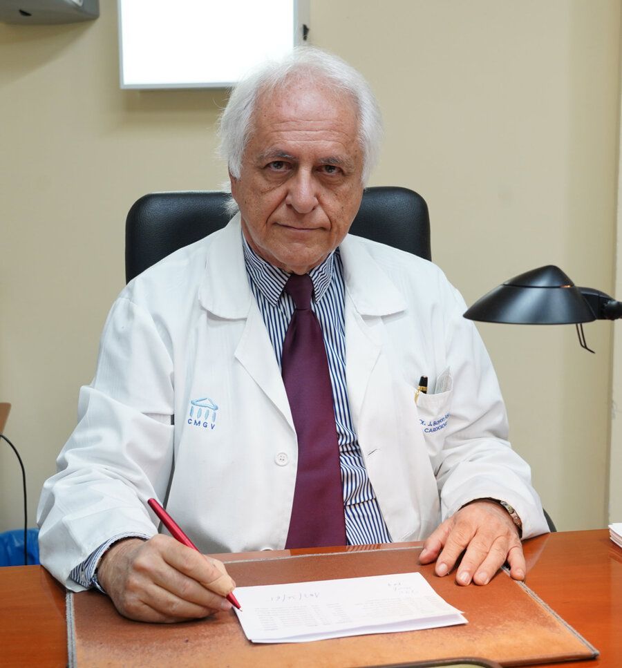 Un médico con bata blanca se sienta en una sala de exámenes con equipo médico.