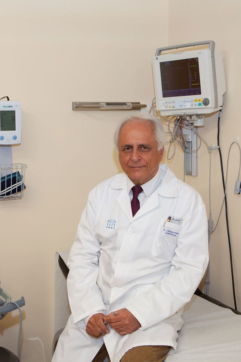 Un médico con bata blanca se sienta en una sala de exámenes con equipo médico.