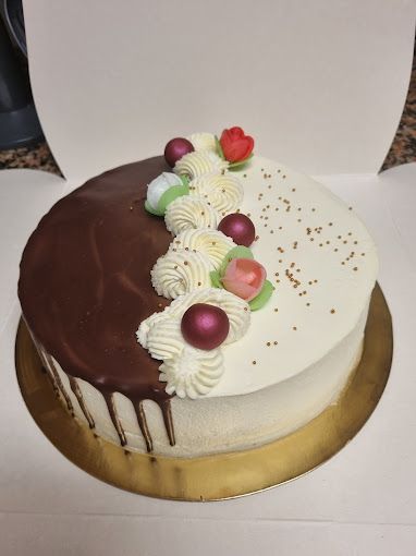 Un pastel de chocolate y blanco con flores encima viene en una caja.