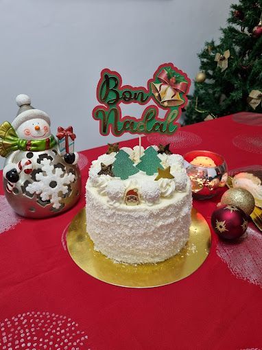 Un pastel de Navidad está sobre una mesa al lado de un árbol de Navidad.