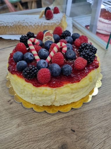 Una tarta de queso con bayas y bastones de caramelo encima está sobre una mesa de madera.