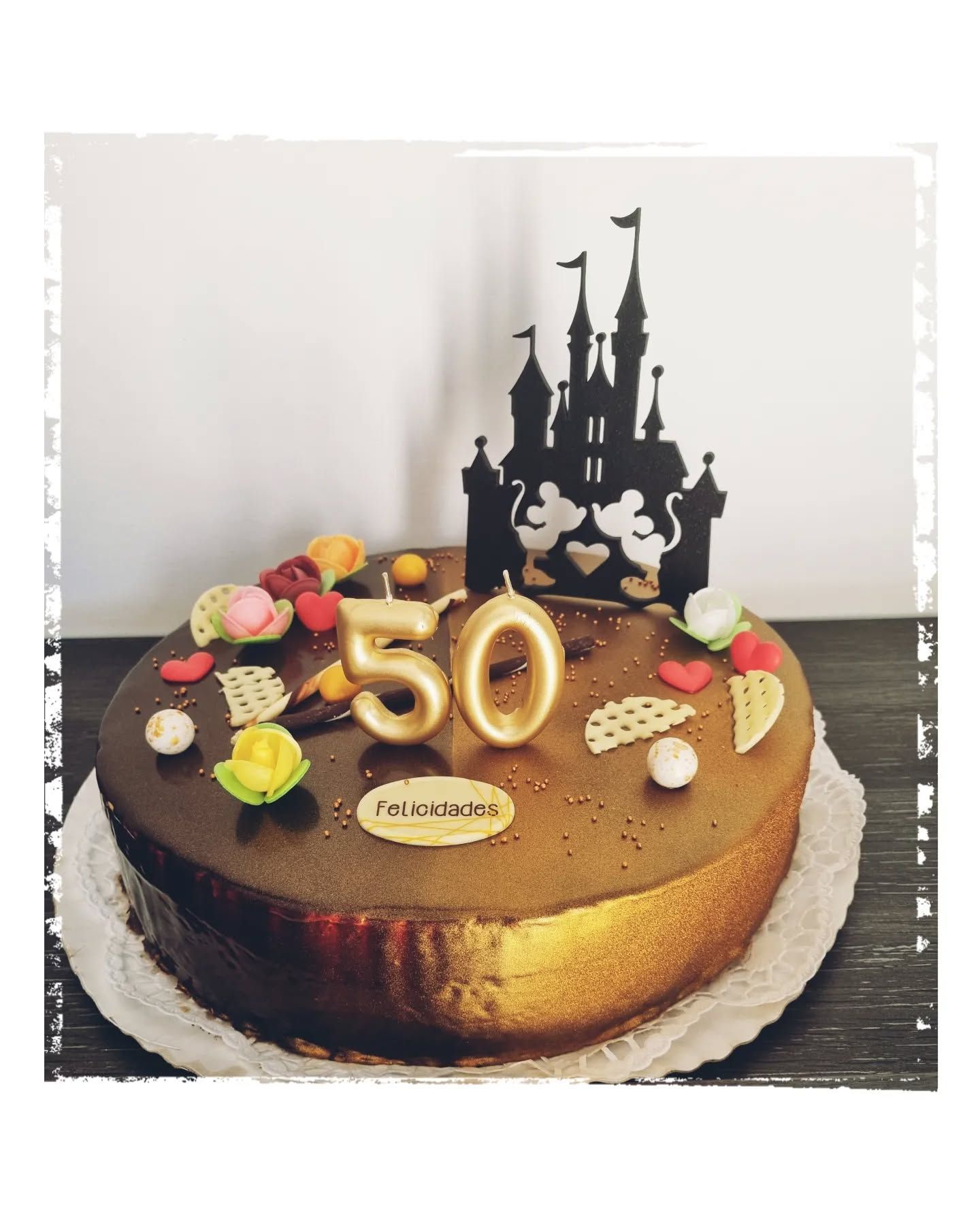 Una tarta de cumpleaños número 50 con un castillo de Mickey Mouse como adorno