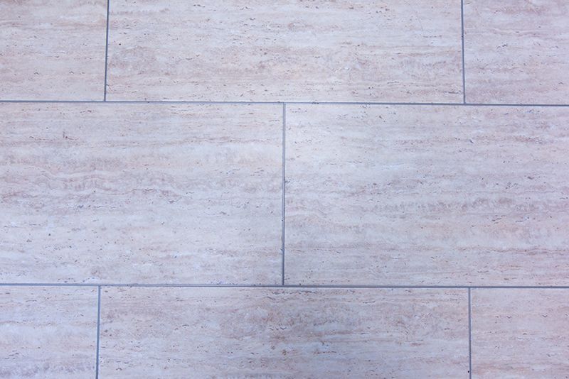 Hellbeige, rechteckige Fliesen, die in einem Rastermuster angeordnet sind.