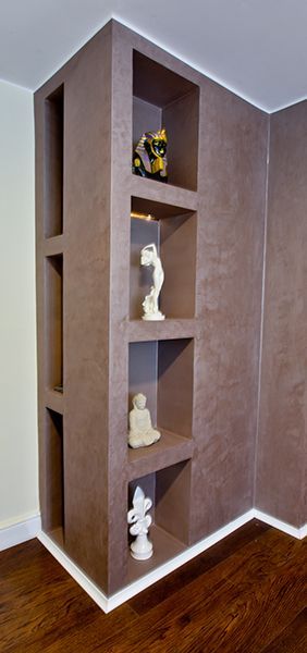 Eingebaute Eckregale mit Skulpturen in einem Raum mit Hartholzböden.