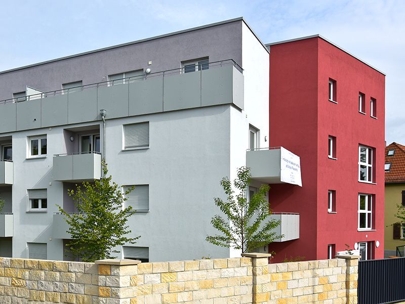 Modernes Mehrfamilienhaus mit roten, weißen und grauen Abschnitten