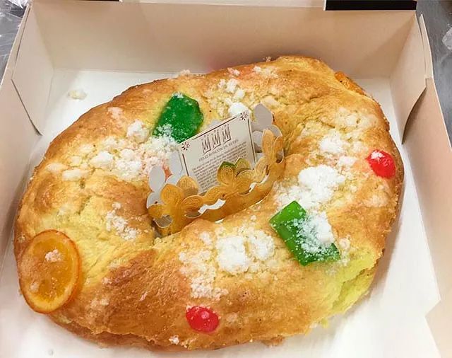 Una hogaza de pan con azúcar en polvo y cerezas en una caja.