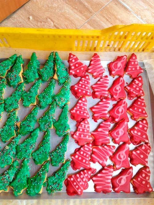 Una bandeja de galletas navideñas rojas y verdes en forma de árboles.