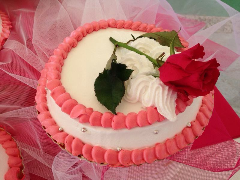 Un pastel rosa y blanco con una rosa roja encima.