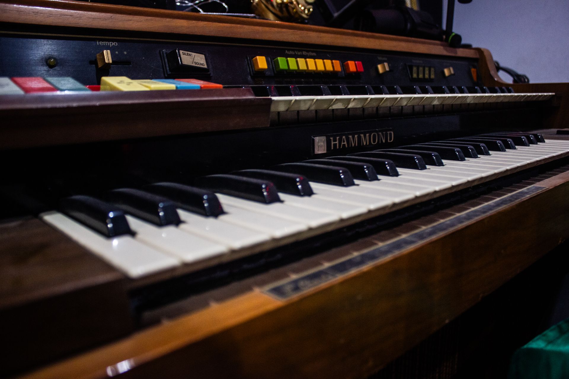 Primer plano de un órgano Hammond antiguo con dos teclados, carcasa de madera y controles coloridos.