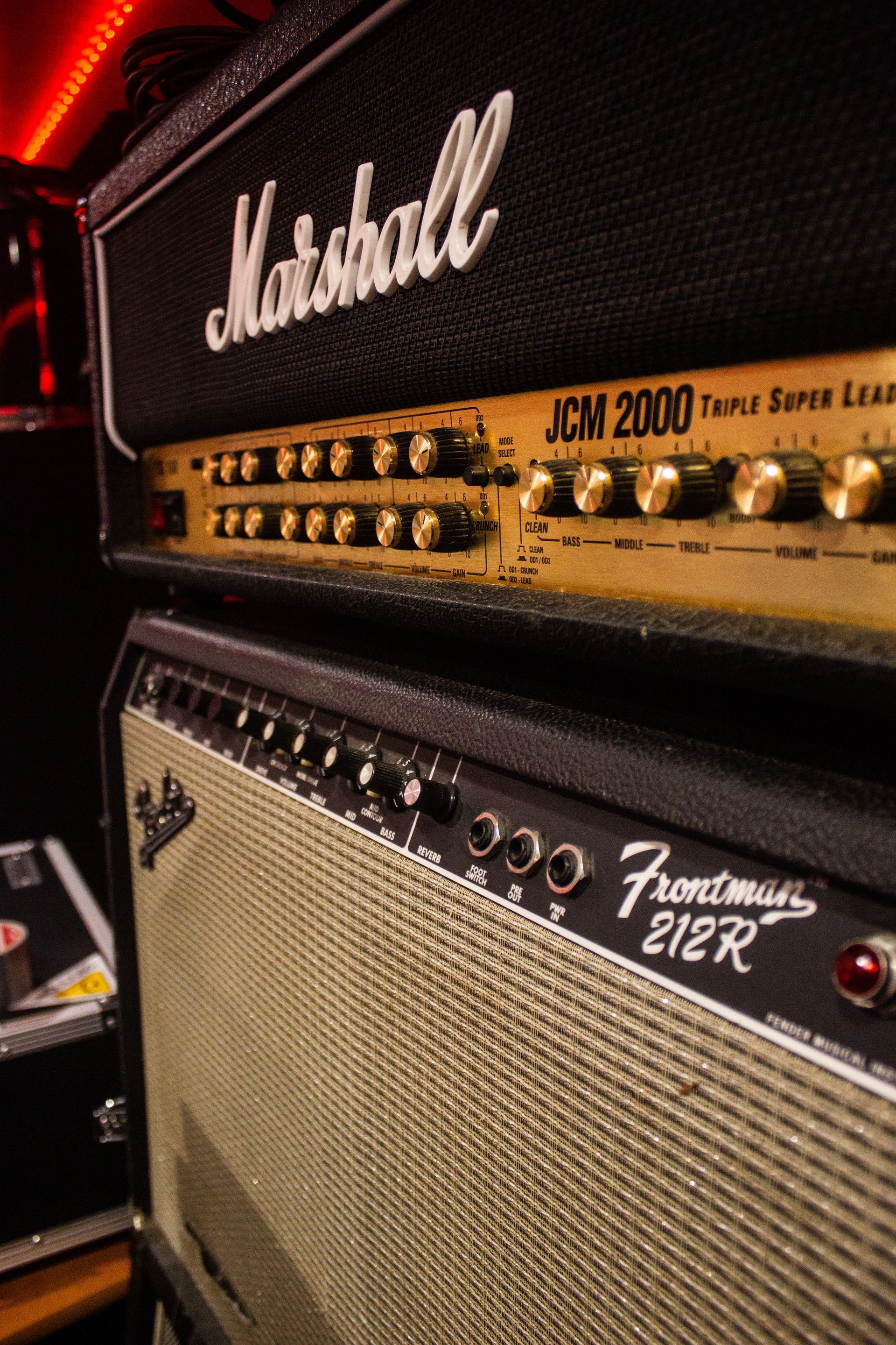Cabezal de amplificador Marshall JCM 2000 sobre un amplificador combo Fender Frontman 212R. Negro y dorado, vista en ángulo.