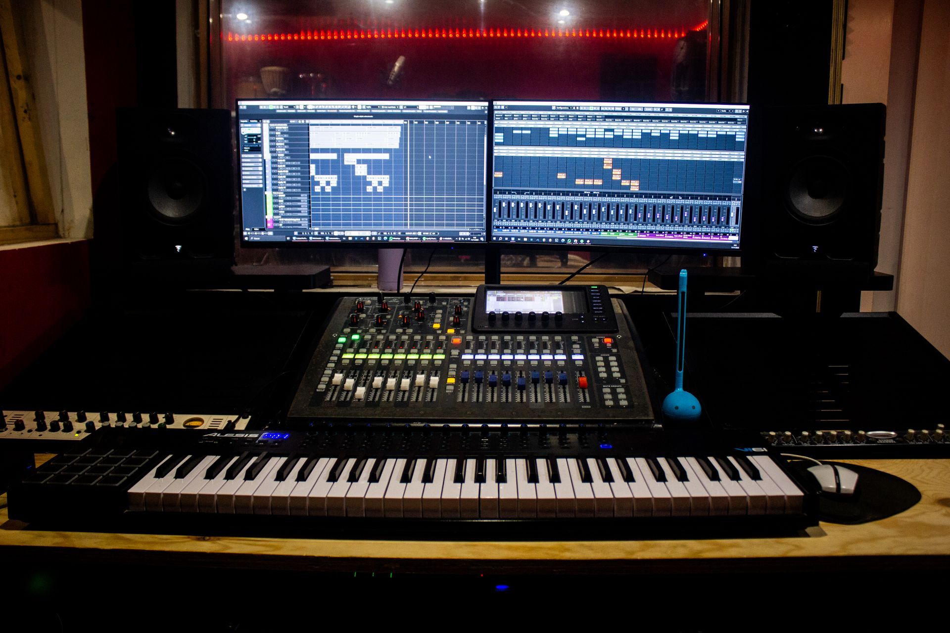 Estudio de producción musical equipado con dos monitores, mesa de mezclas, teclado y altavoces.