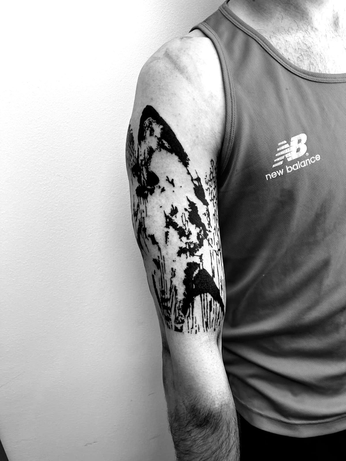 Una fotografía en blanco y negro de un hombre con un tatuaje en el brazo.