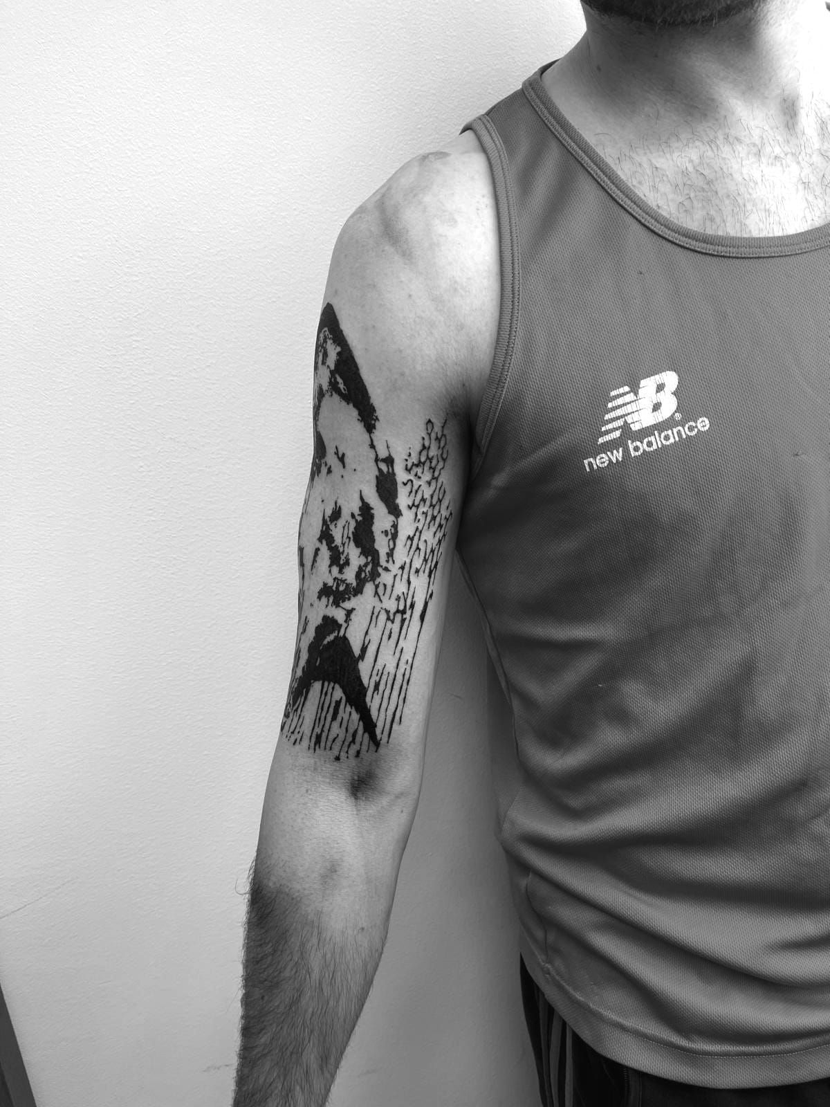 Un hombre con un tatuaje en el brazo lleva una camiseta sin mangas New Balance.