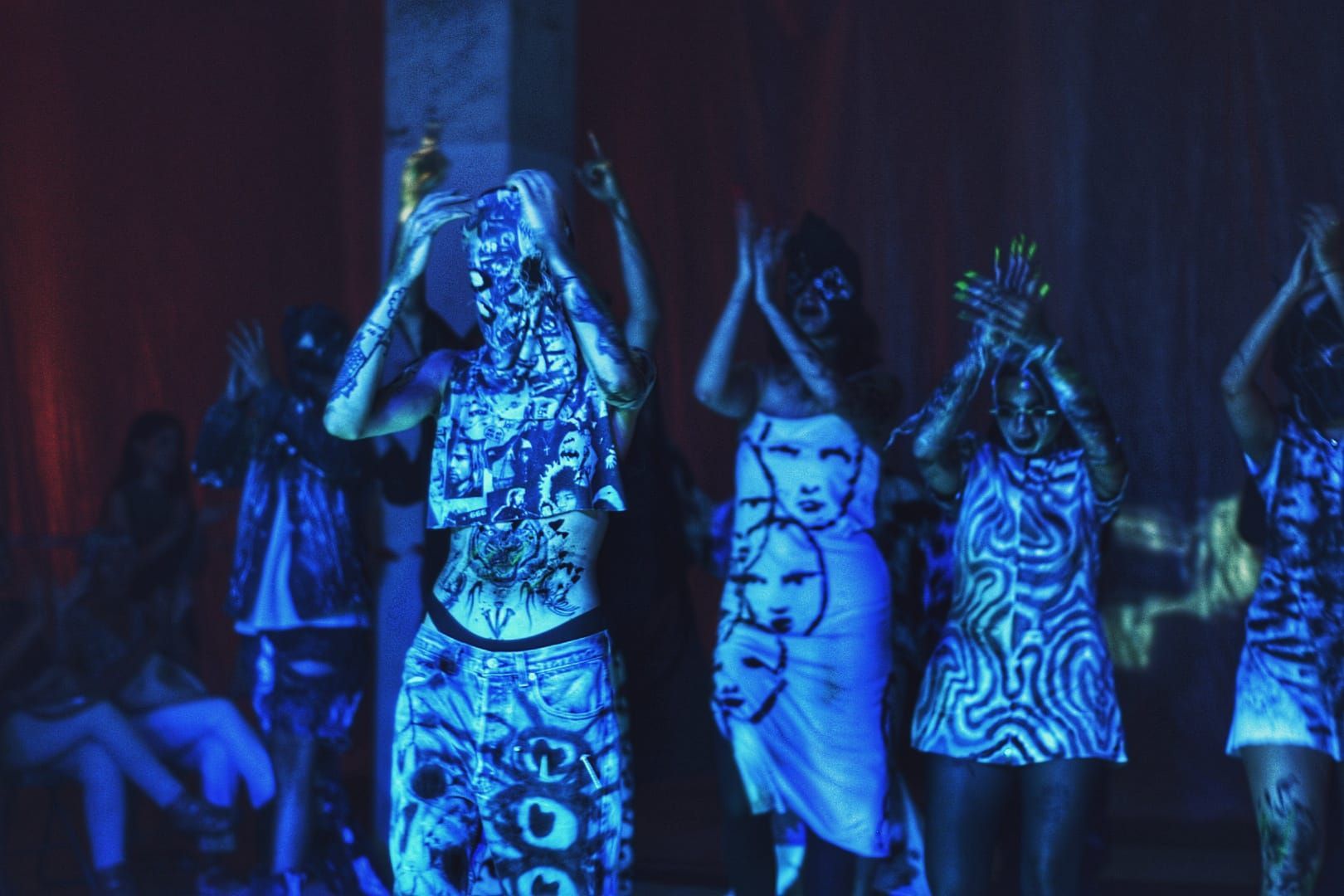 Un grupo de personas están bailando en una habitación oscura.