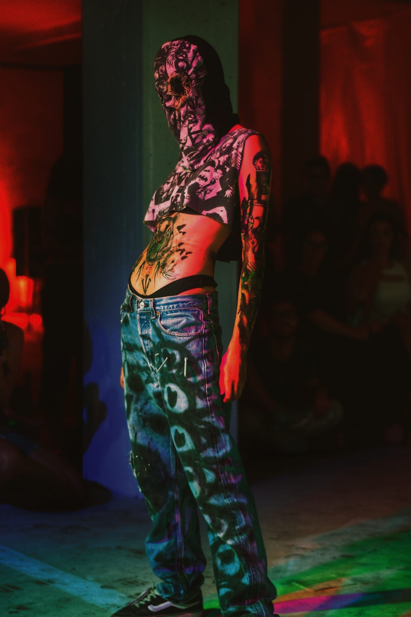 Una mujer con una máscara en la cara está parada en una habitación oscura.