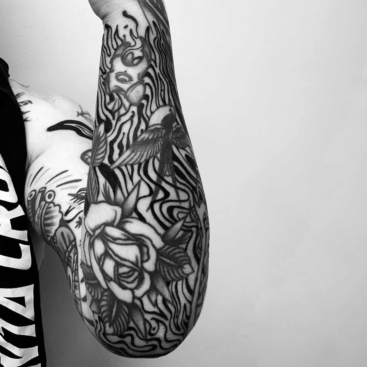 Una fotografía en blanco y negro del brazo de una persona con muchos tatuajes.