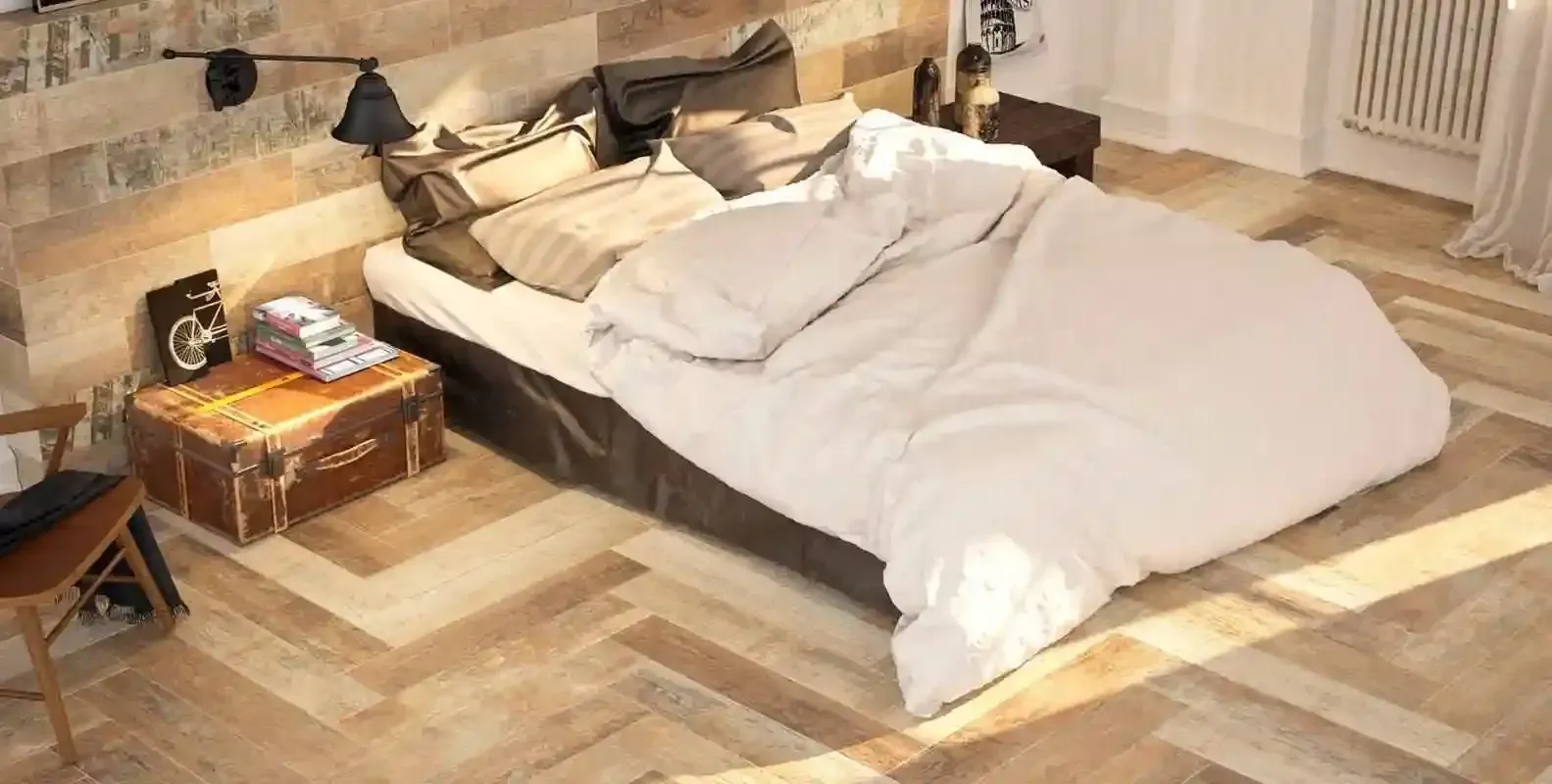 Hay una cama en el medio de la habitación con piso de madera.