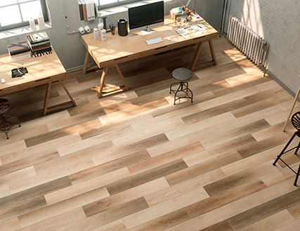 Una habitación con suelo de madera y un escritorio con una computadora encima.
