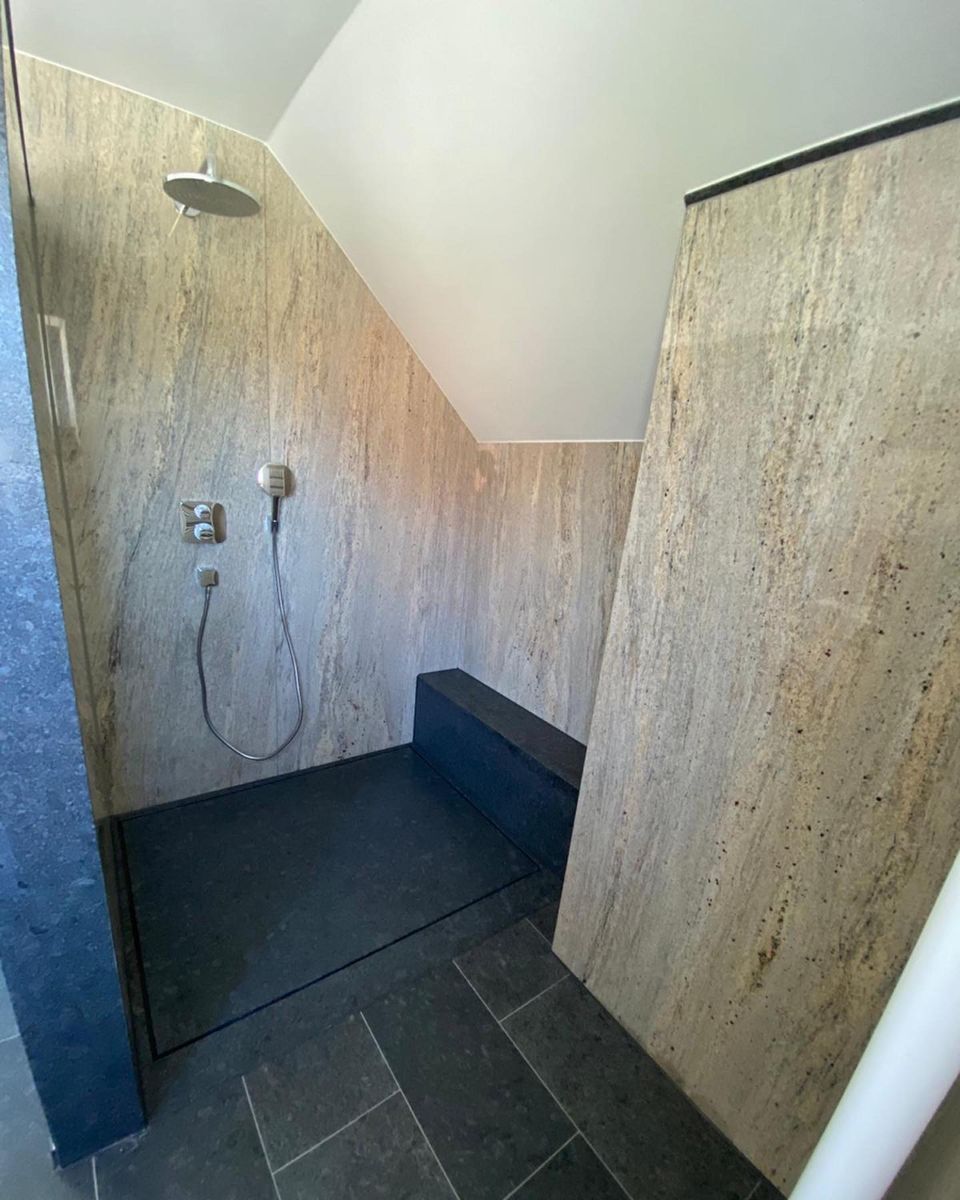 Bodennahe Dusche mit Wänden aus Naturstein