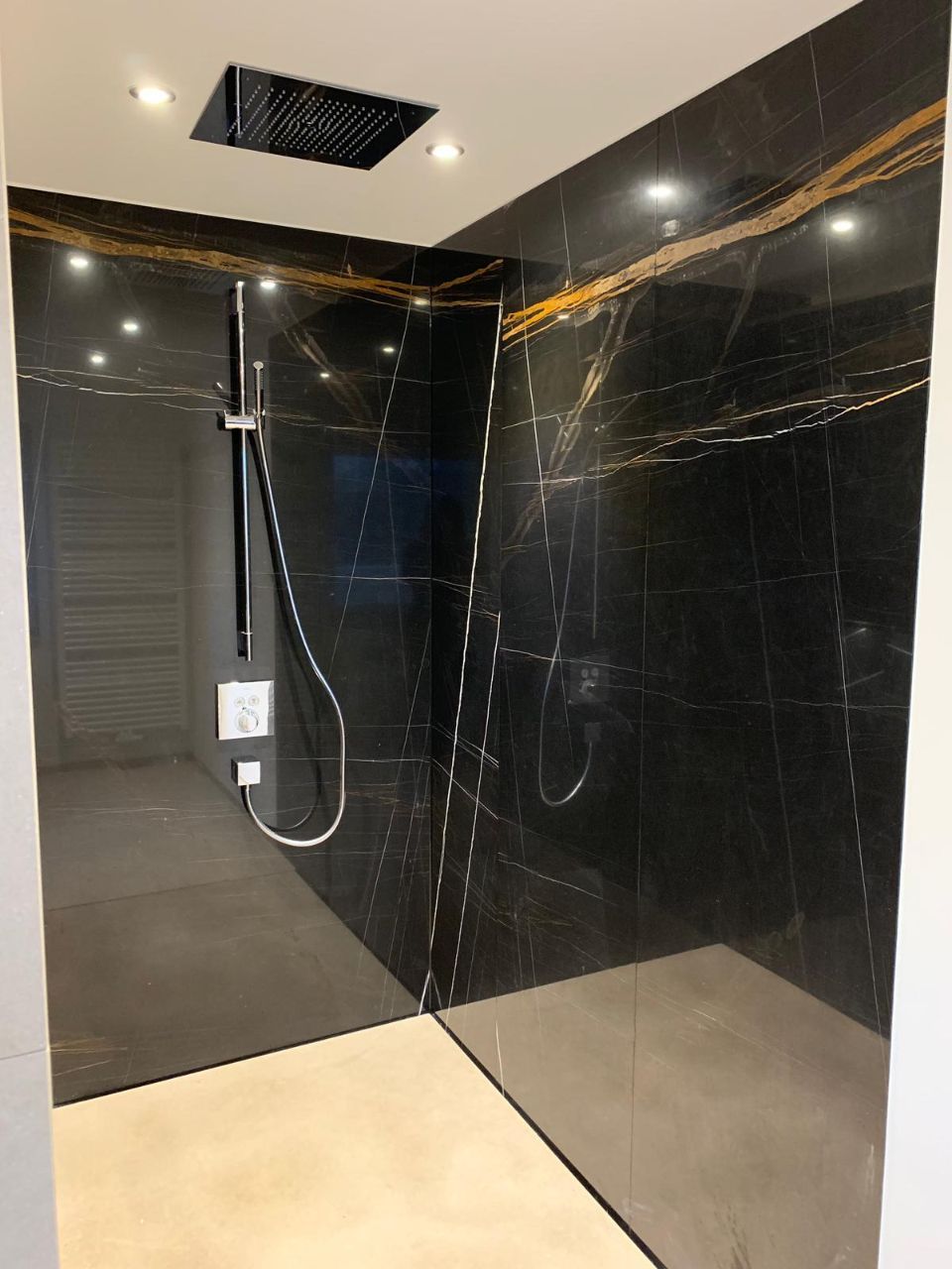 Großzügige Dusche mit dunkler Wand aus Steinfliesen