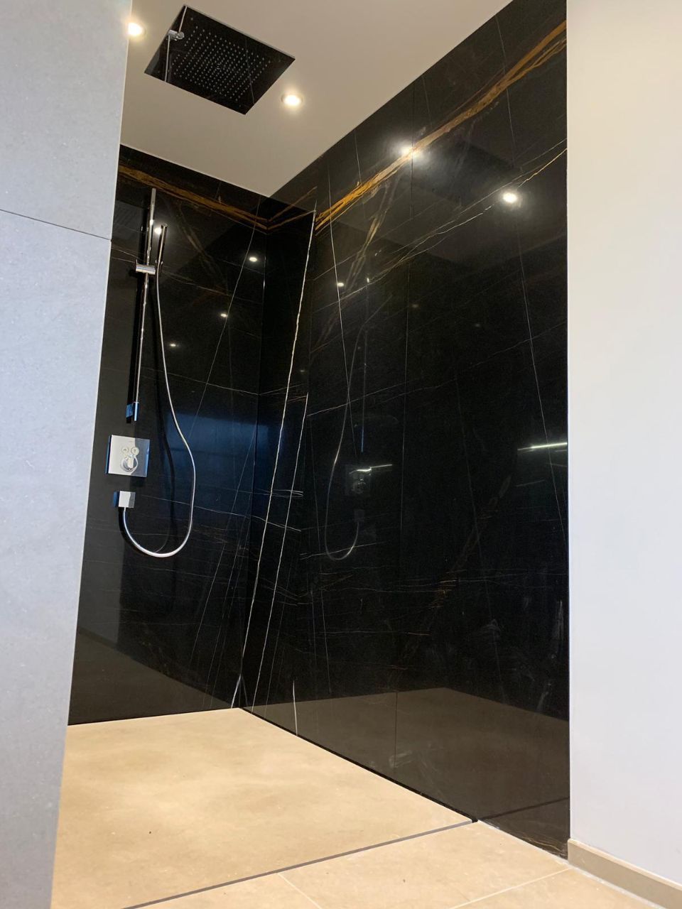 Großzügige Dusche mit dunkler Wand aus Stein