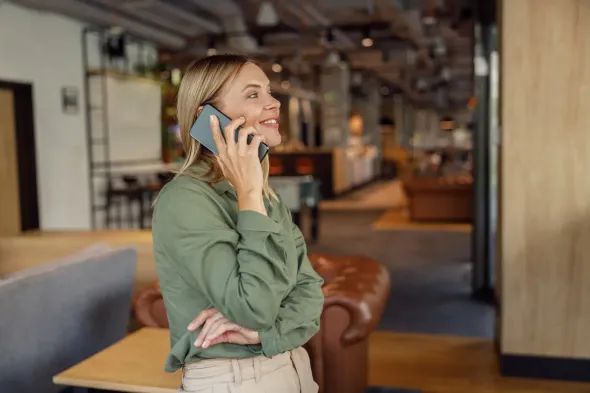 Una persona con una camisa verde habla por teléfono móvil mientras está de pie en el vestíbulo de una oficina.