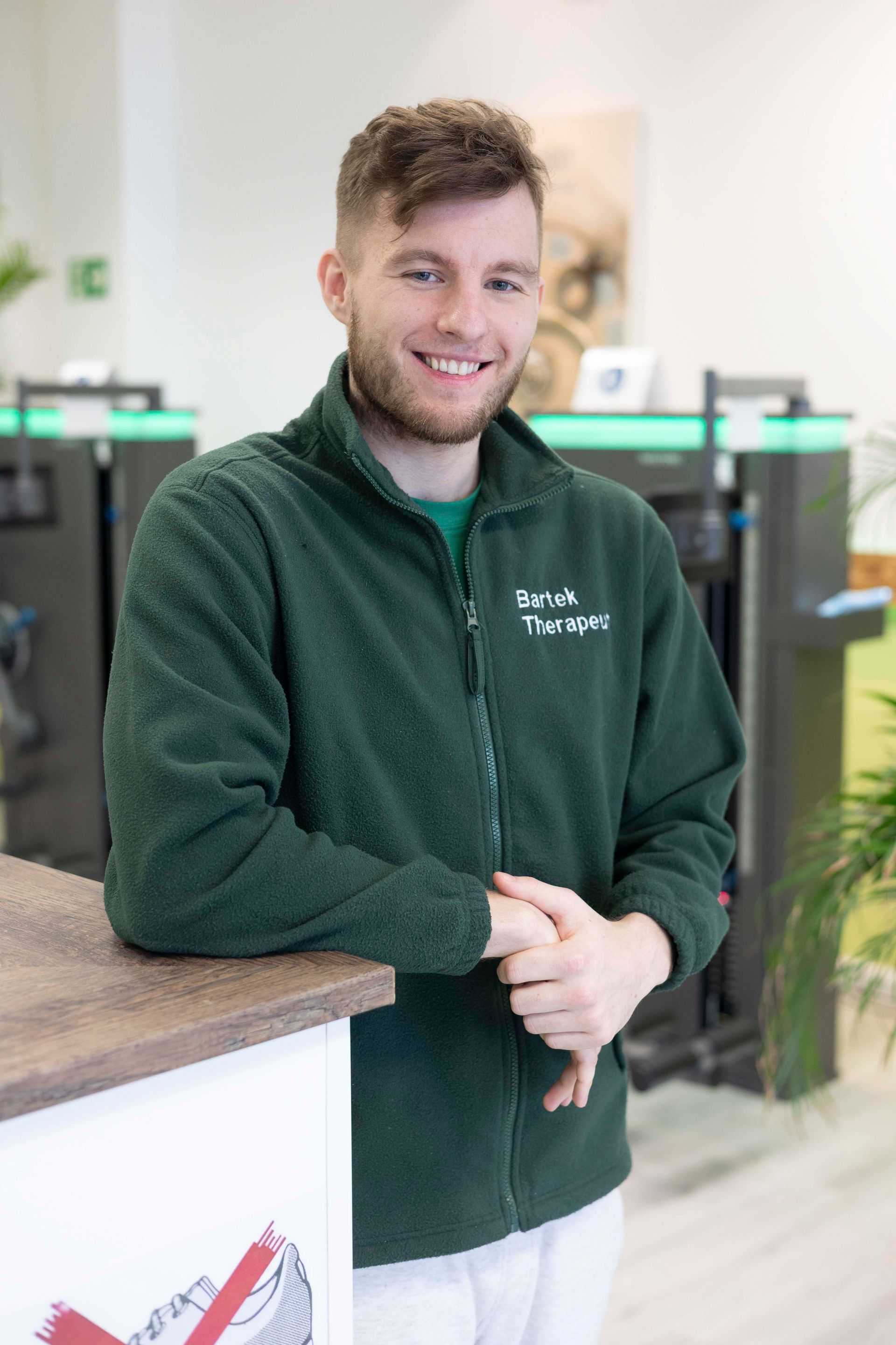 Mann mit Kapuzenpullover vor grünem Hintergrund, der den Betrachter direkt anblickt.