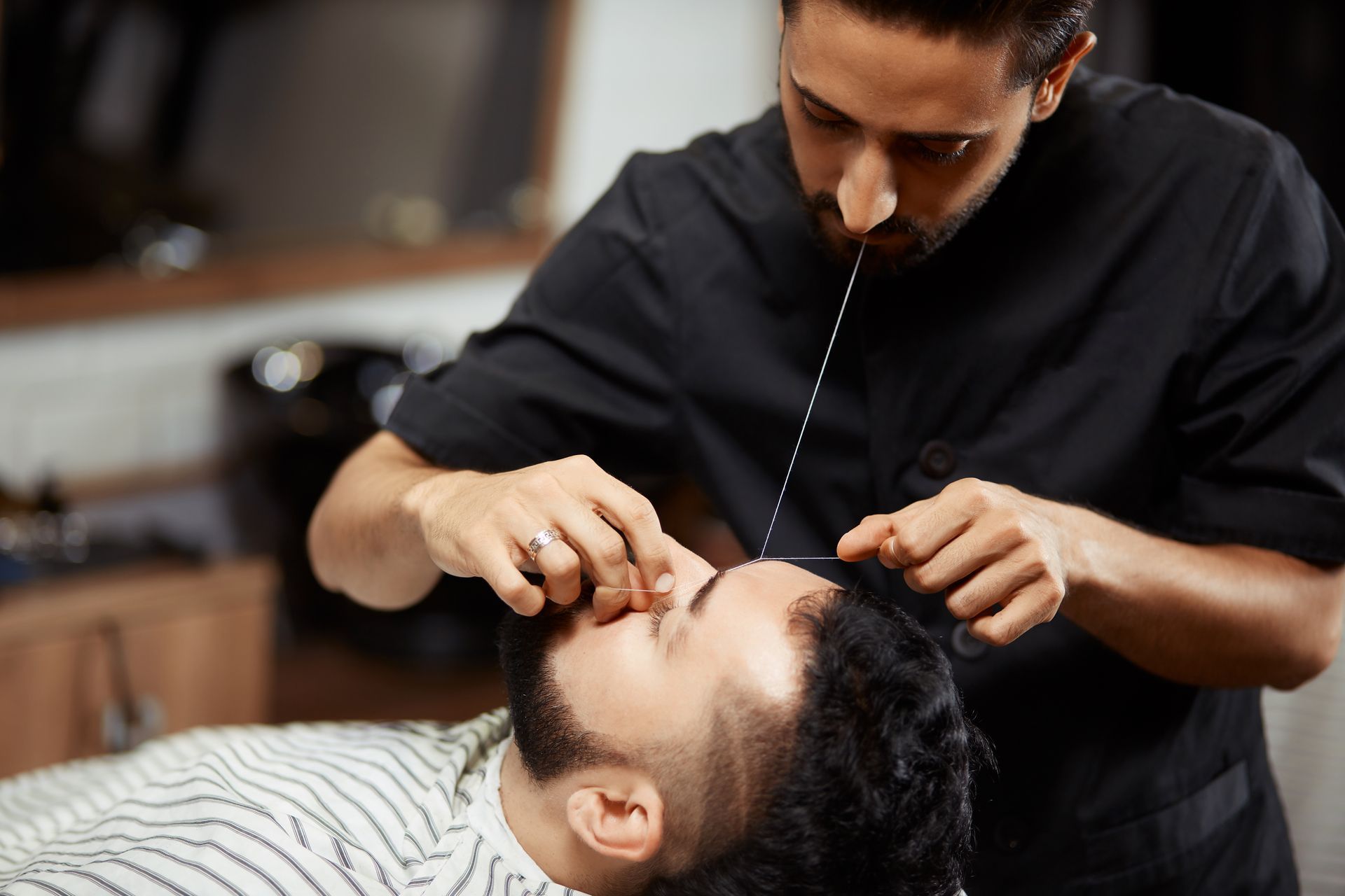 Ein Mann lässt sich in einem Friseursalon von einem Friseur Haare entfernen.