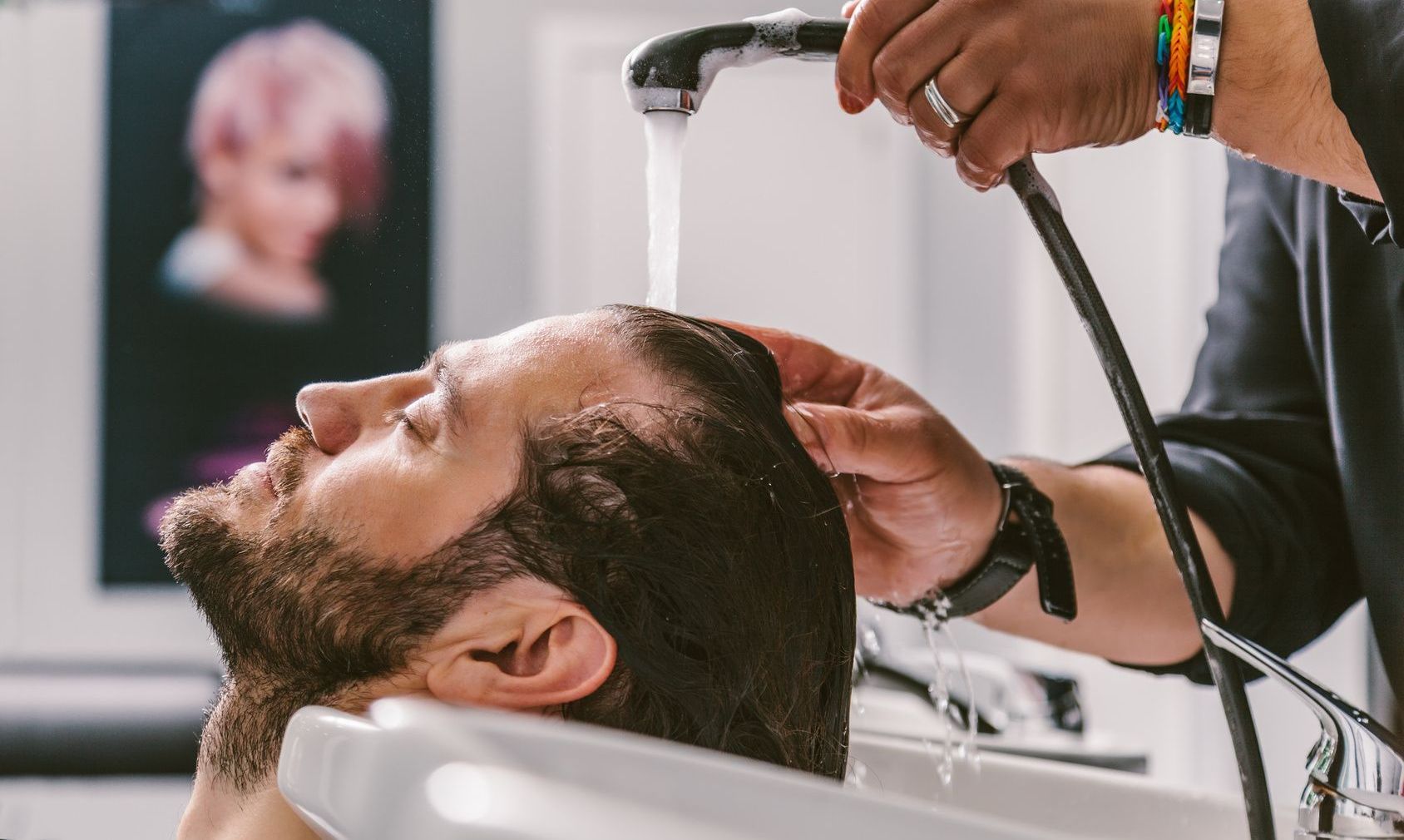 Ein Mann lässt sich in einem Salon von einem Friseur die Haare waschen.