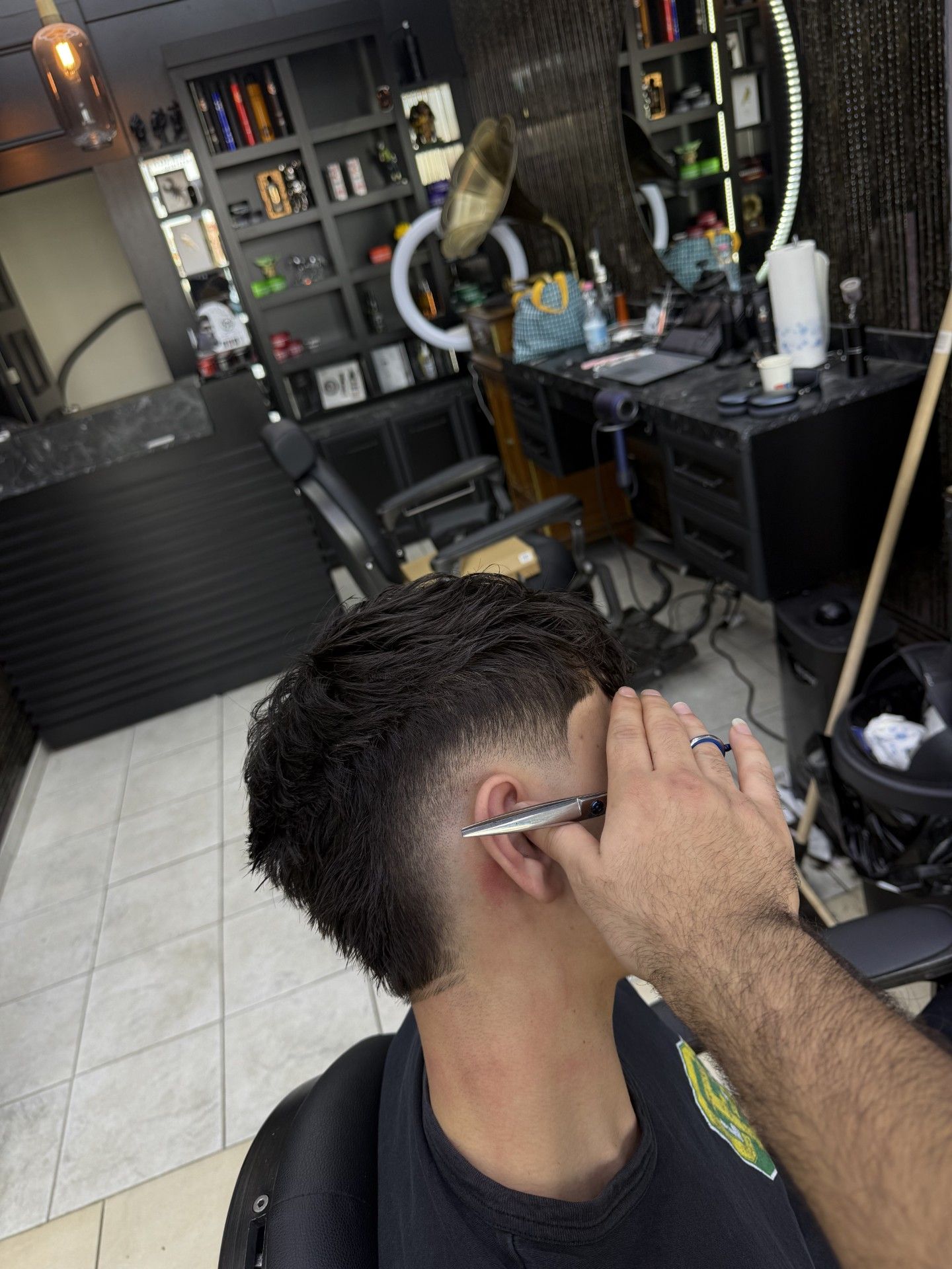 Ein Mann mit Bart sitzt in einem Friseurstuhl und lächelt. Foto vom Ado Barbershop, Inh. Bijo