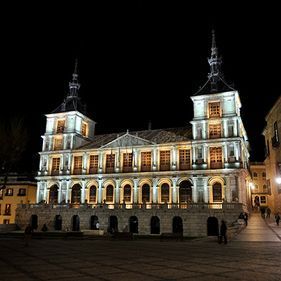 Un gran edificio está iluminado por la noche en una ciudad.