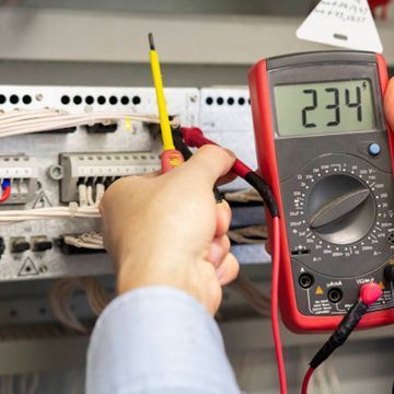 Una persona sostiene un multímetro con el número 234.