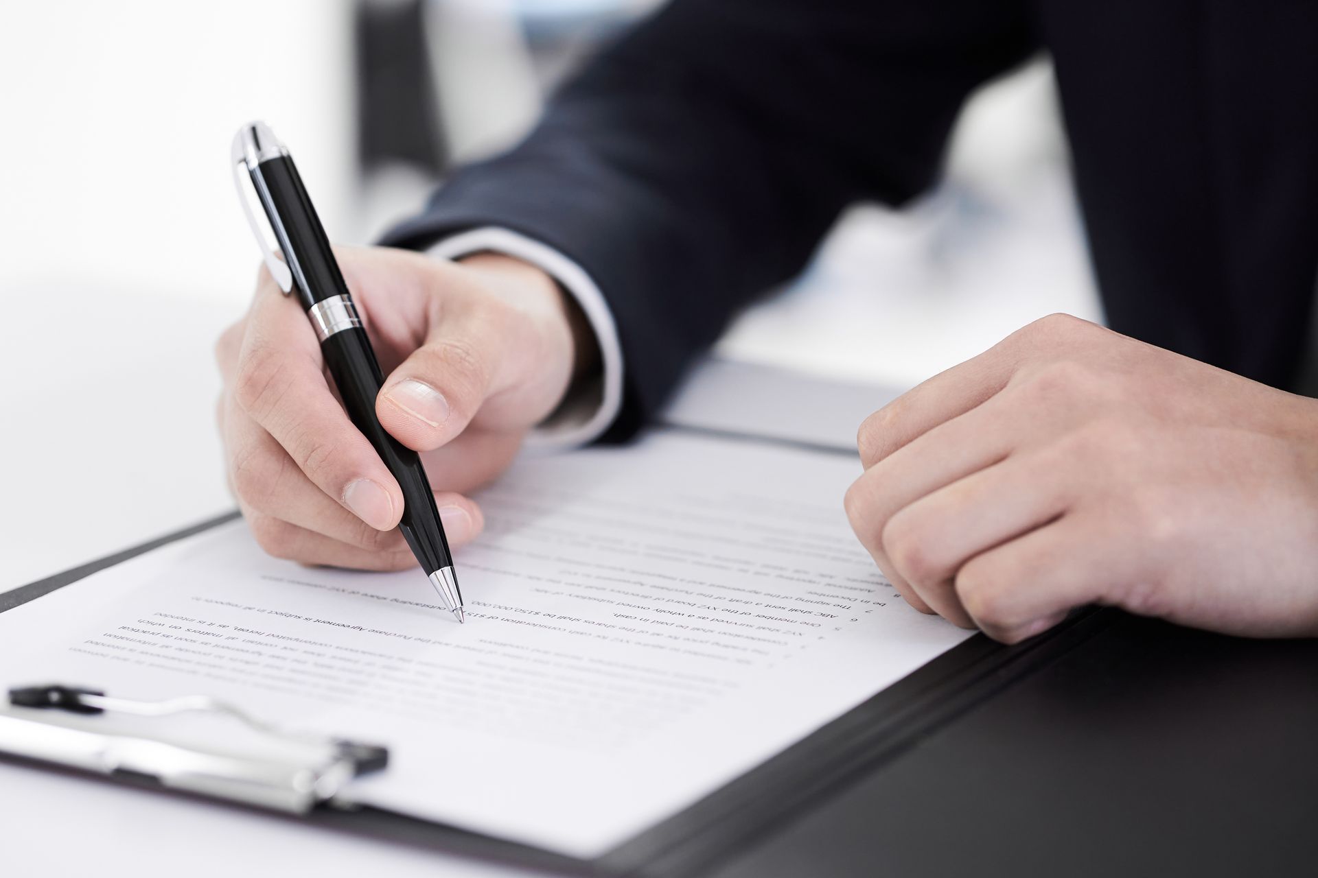 Eine Person schreibt mit einem Stift auf ein Blatt Papier.