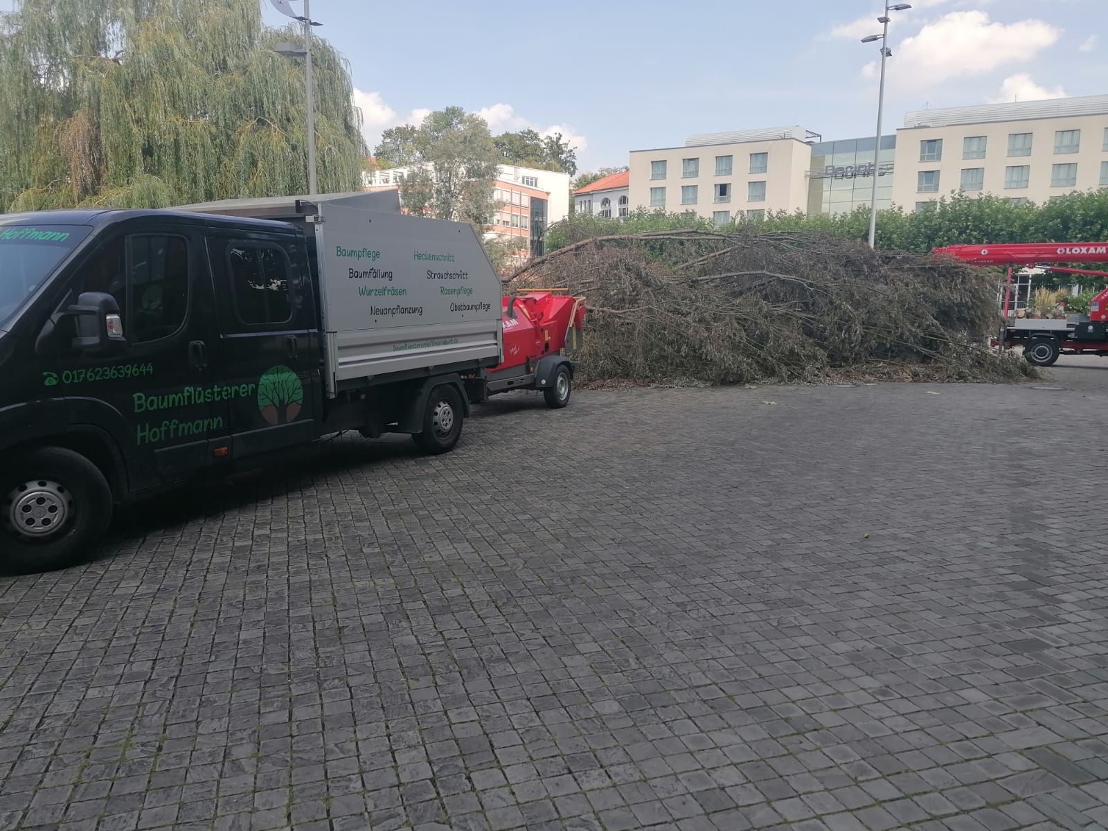 Firmenfahrzeuge auf einem Betriebshof im Einsatz bei Garten- und Baumpflegearbeiten.