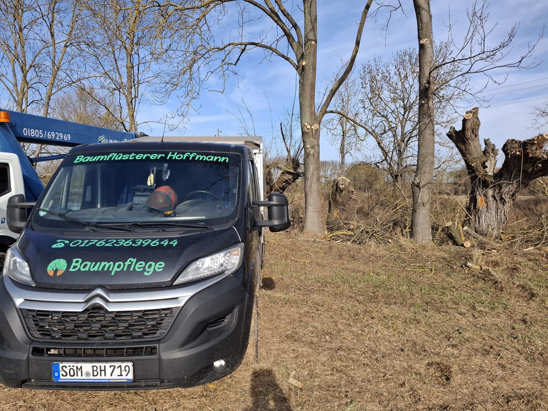 Firmenfahrzeug eines Baumpflegebetriebs auf Einsatz im Gelände.