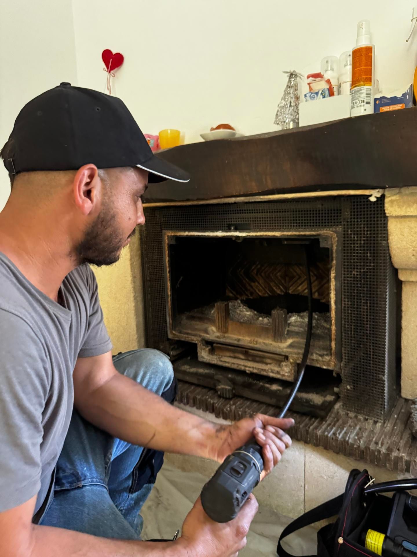 Un ramoneur avec une casquette devant une cheminée.