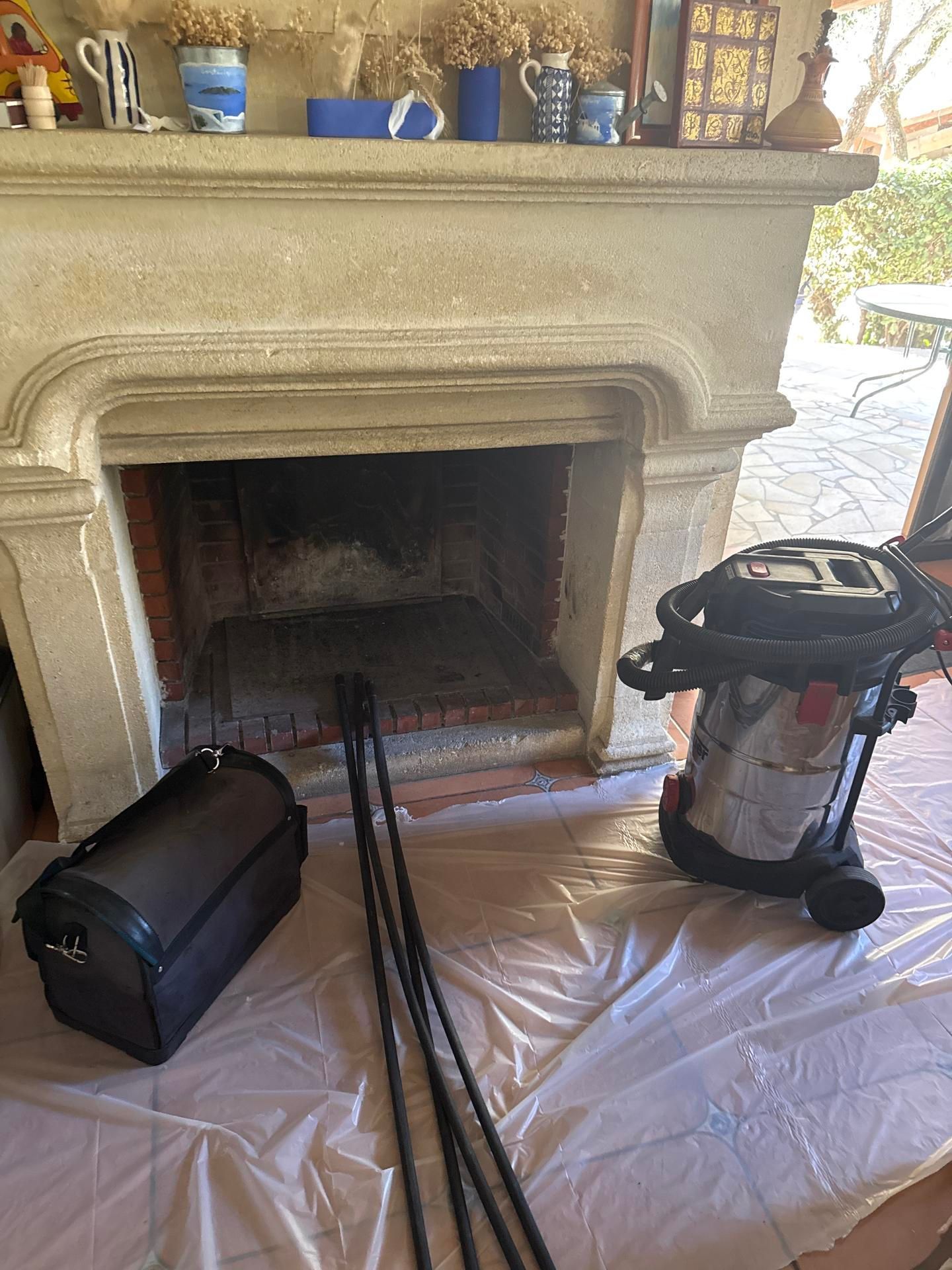 Matériel de ramonage devant une cheminée propre.