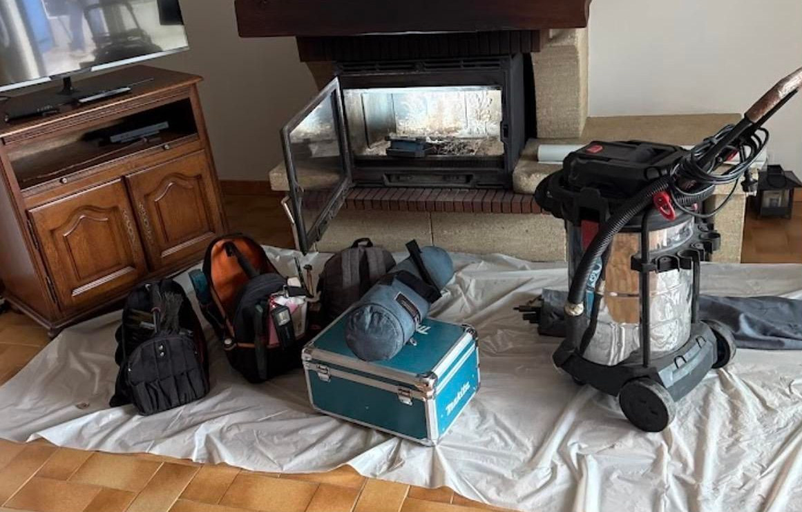 Matériel de ramonage devant une cheminée avec insert.