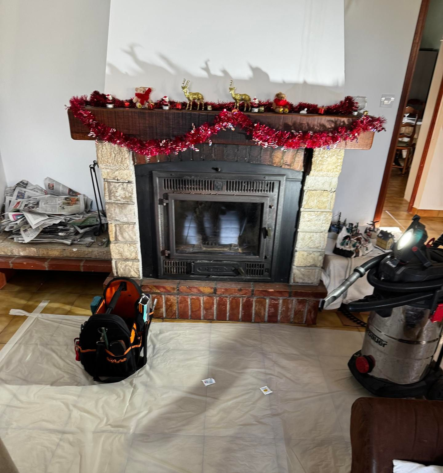 Une cheminée avec une guirlande rouge.