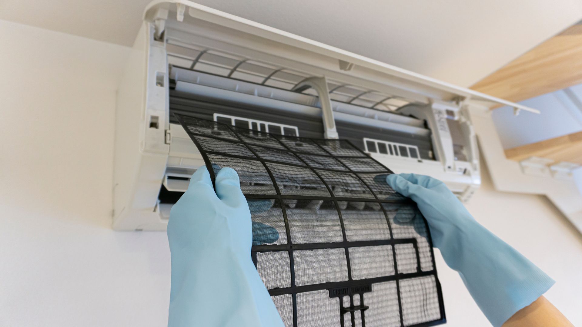 Le filtre d'un climatiseur et des gants bleus.