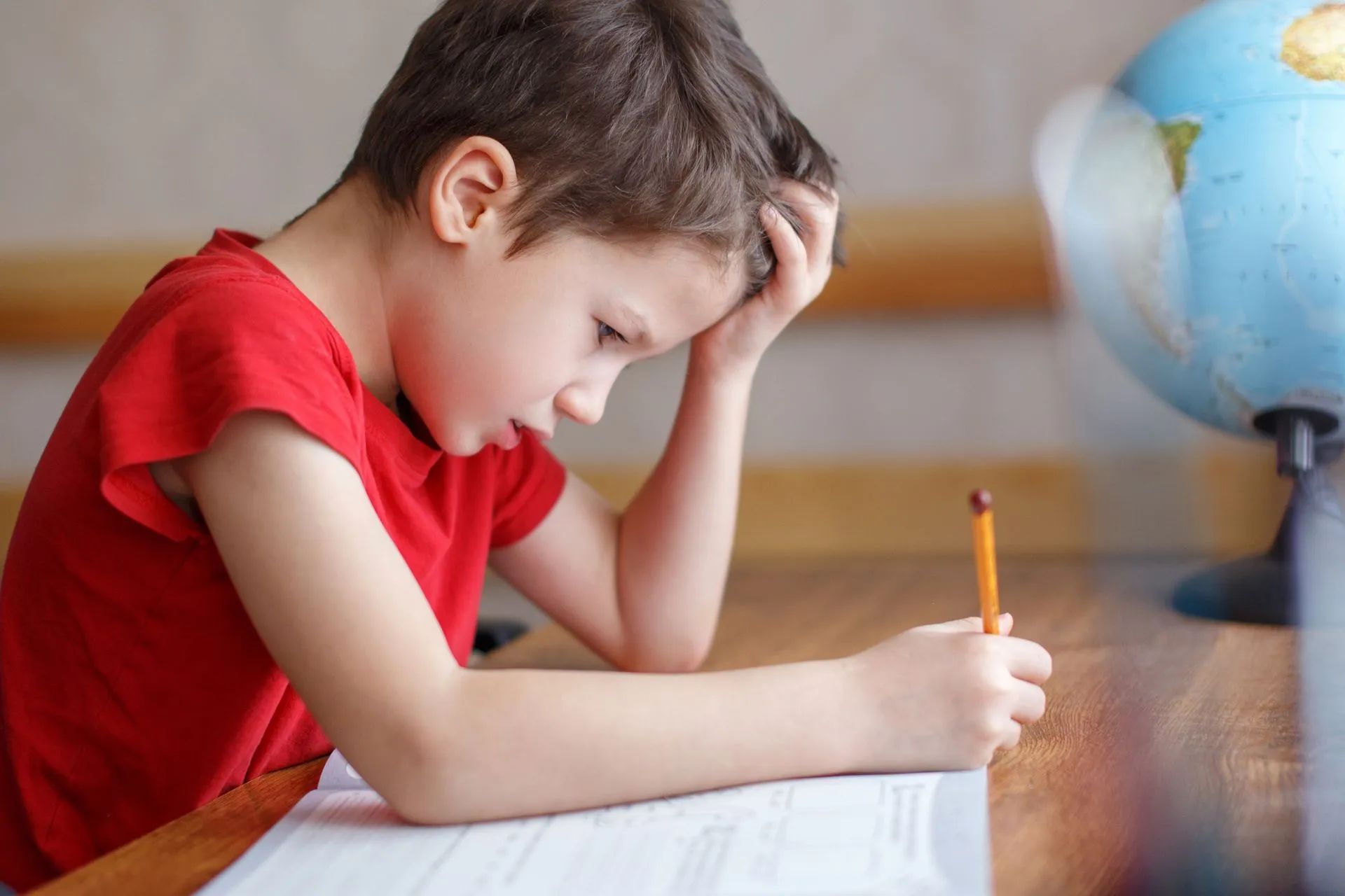 Enfant au t-shirt rouge faisant ses devoirs