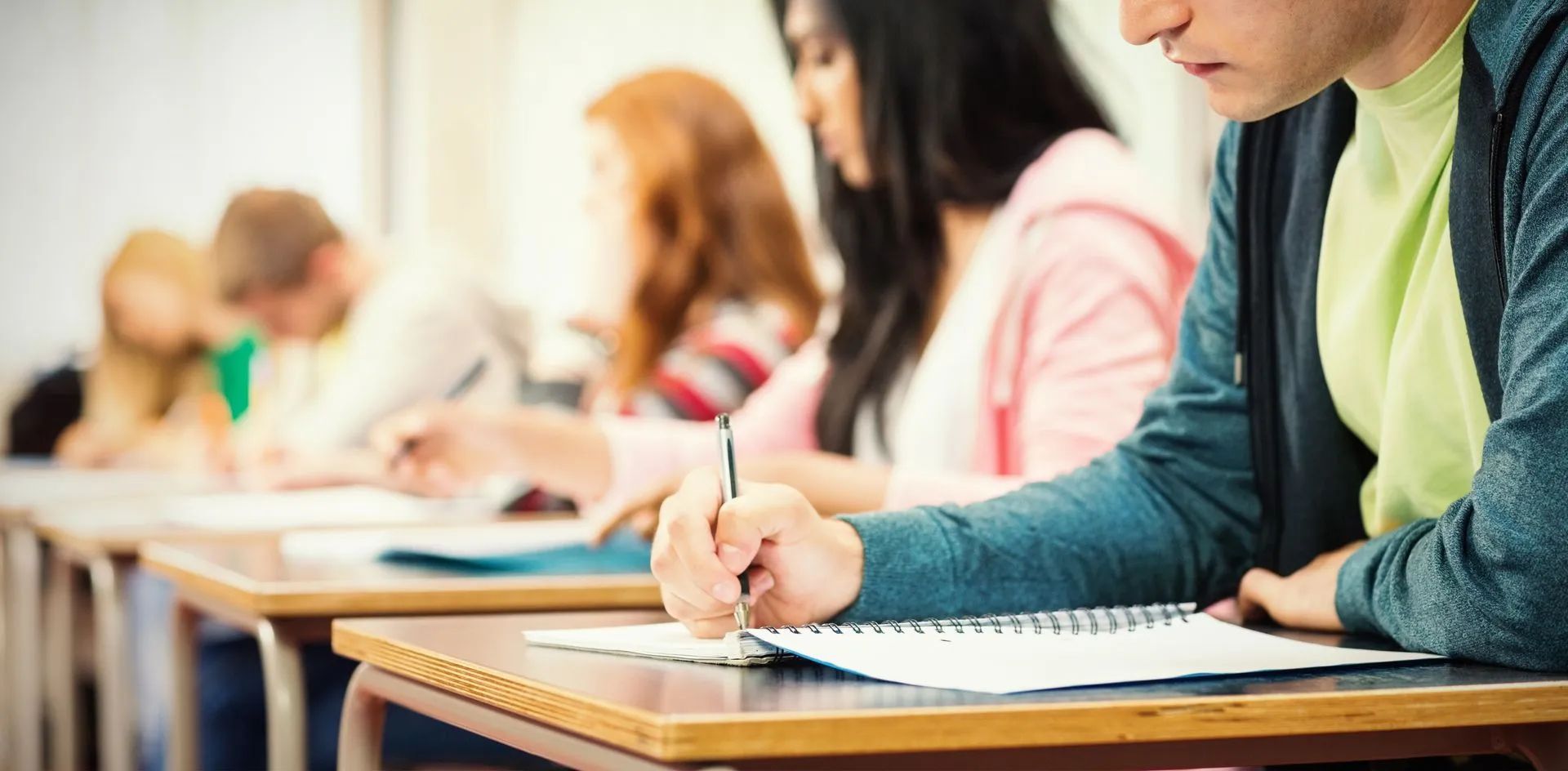 Étudiants en plein examen, gros plan sur une jeune femme en train d'écrire