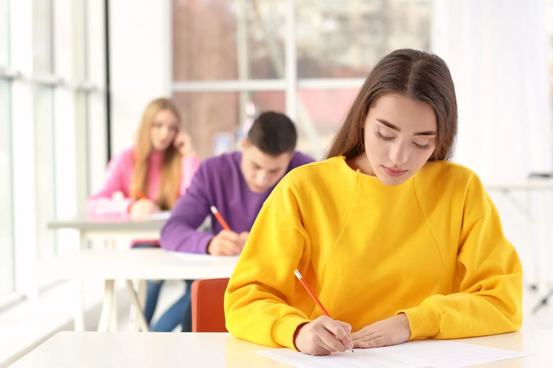 Jeune femme avec un pull jaune passant un examen écrit