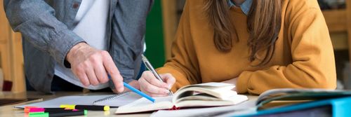 Professeur pointant un livre avec un crayon bleu