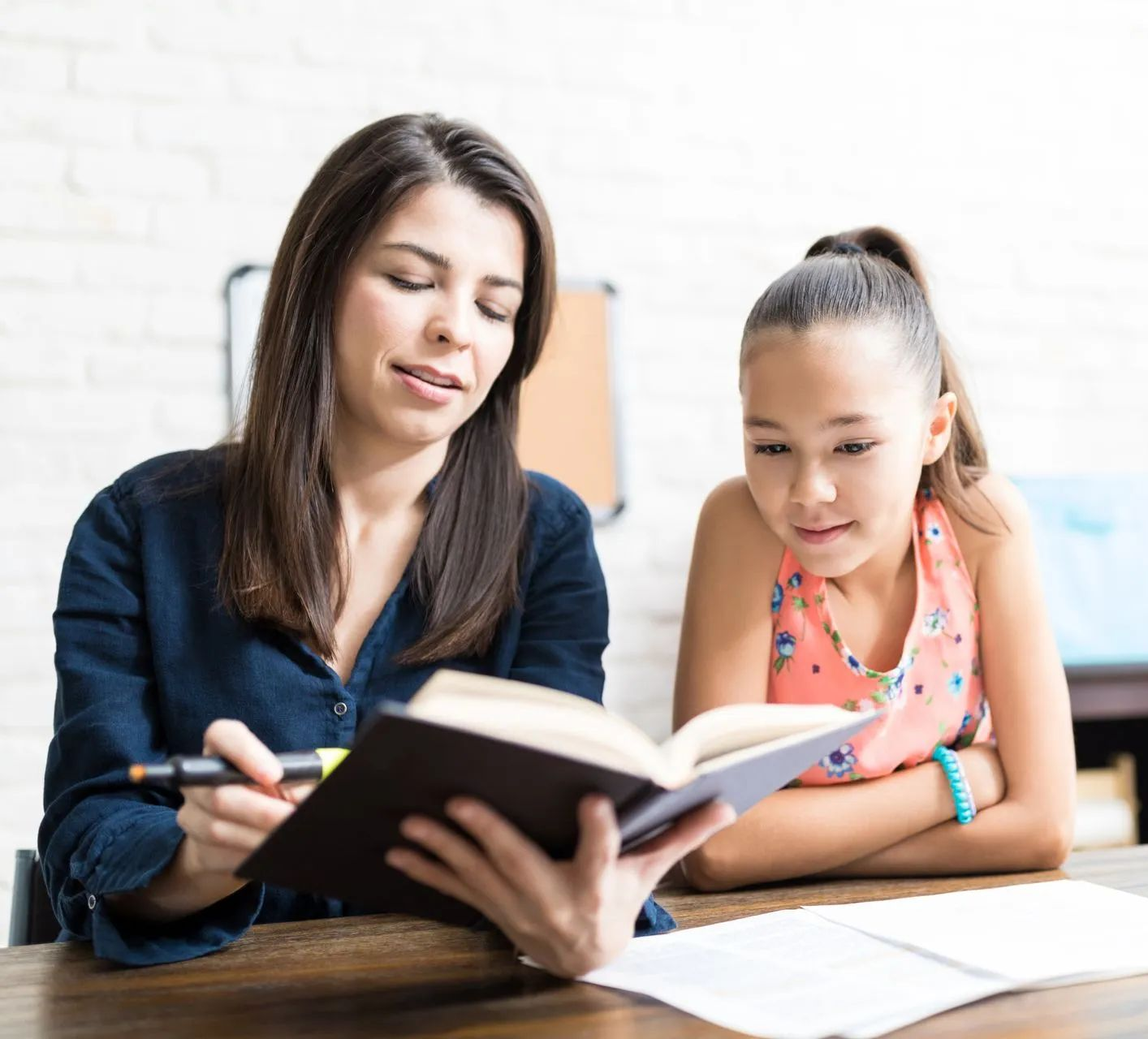 Une femme et une jeune fille lisent ensemble à une table