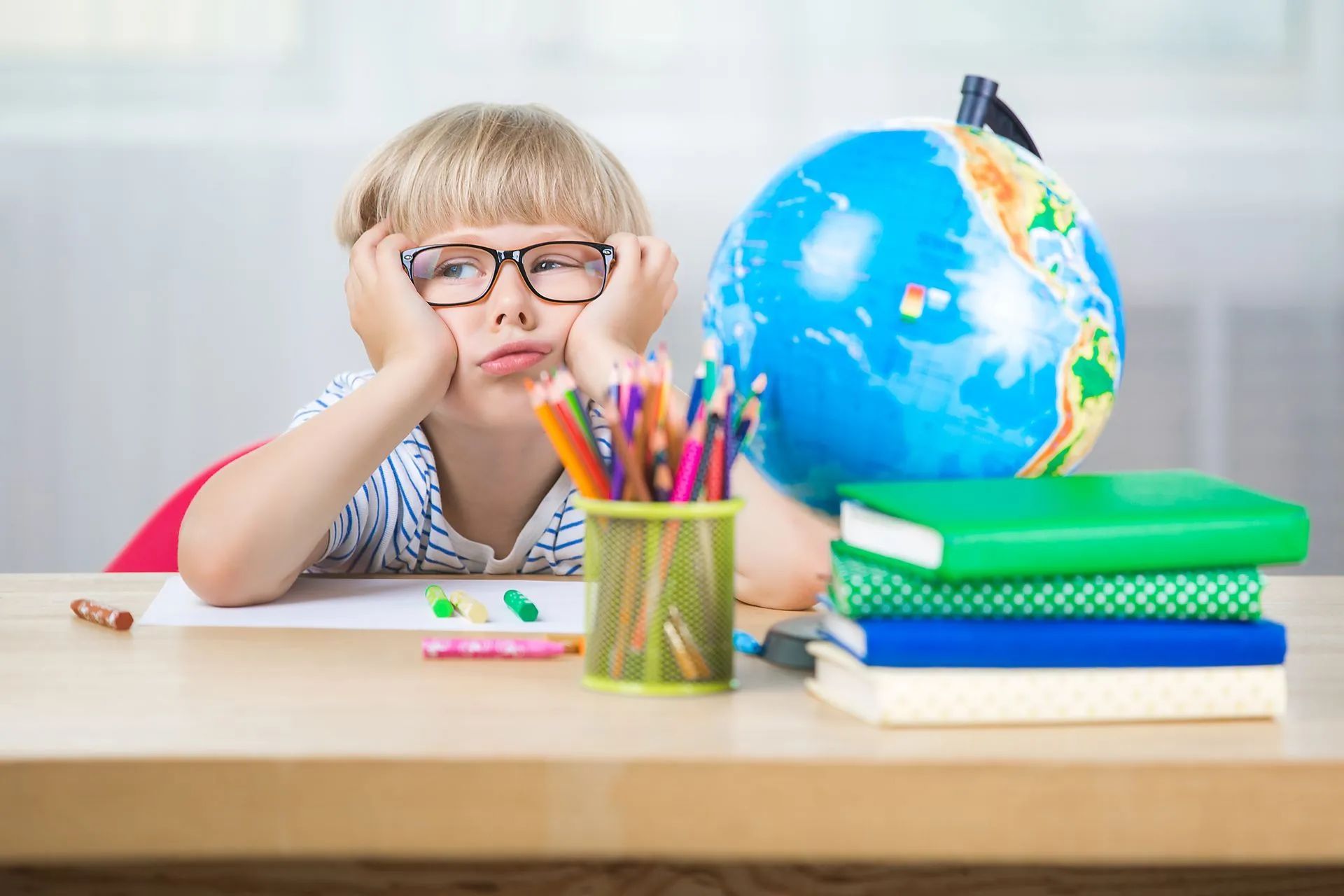 Jeune enfant blond se tient la tête en classe