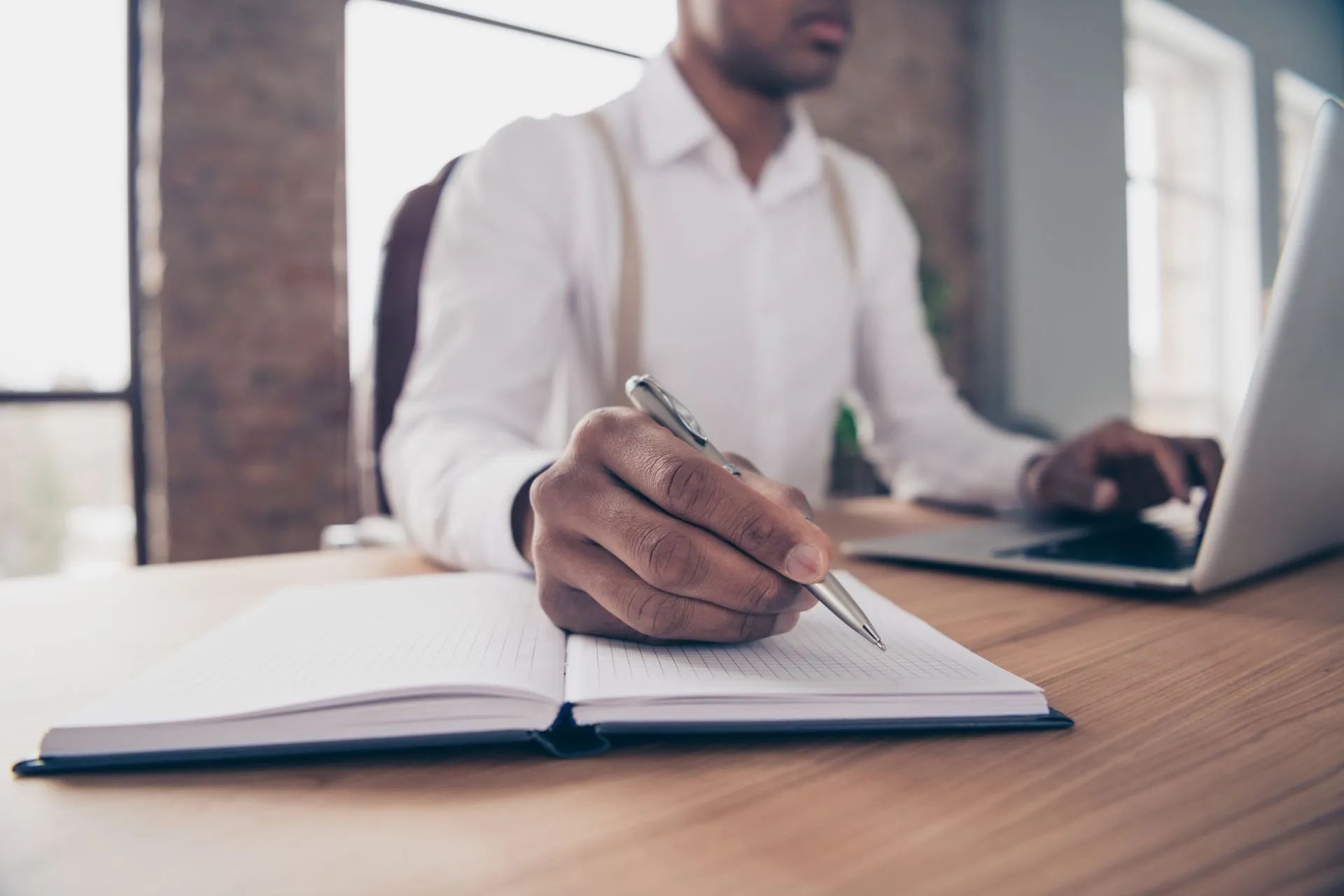 Un homme tient un stylo au-dessus d'une page blanche