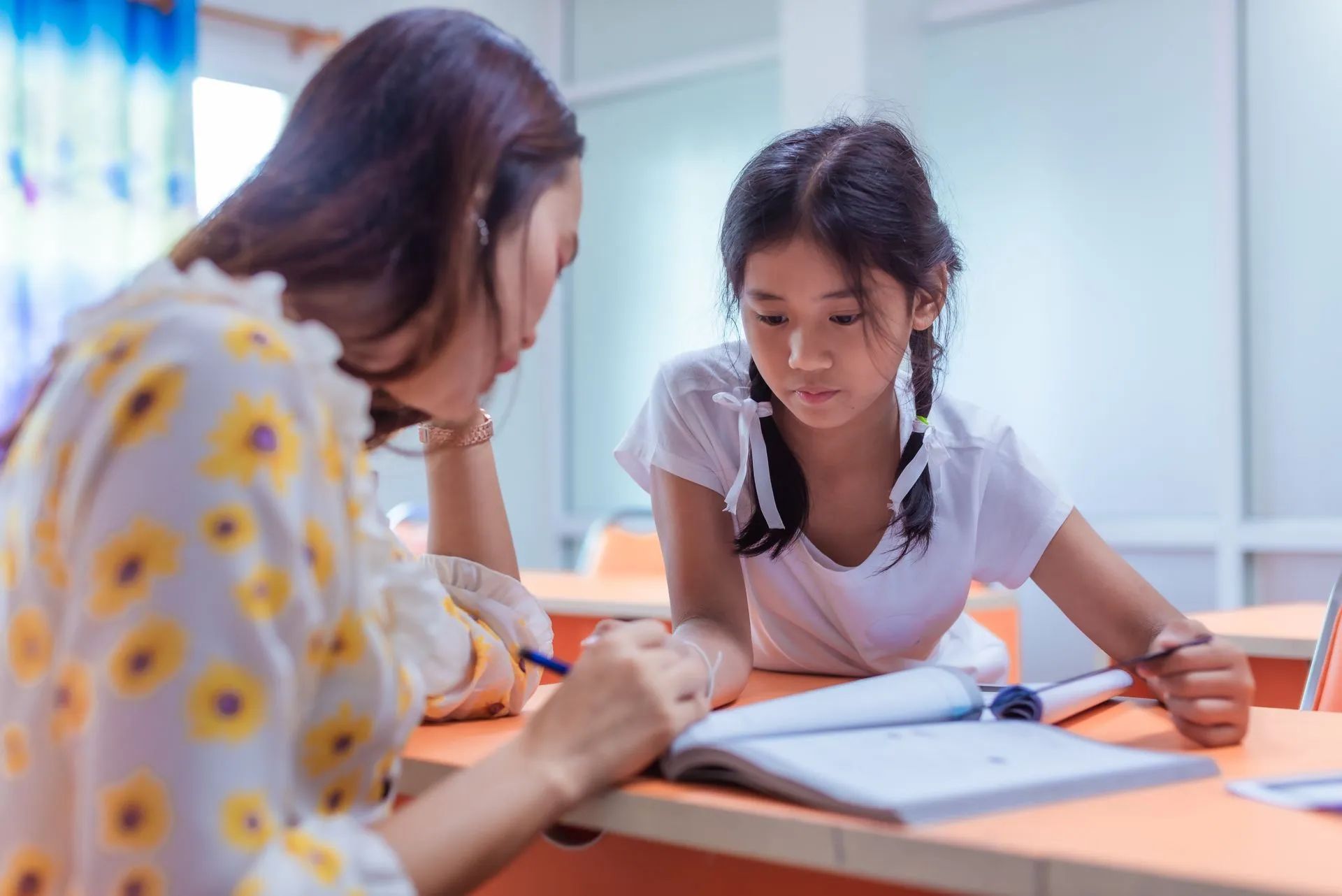 Une femme montrant un manuel d'école à une petite-fille