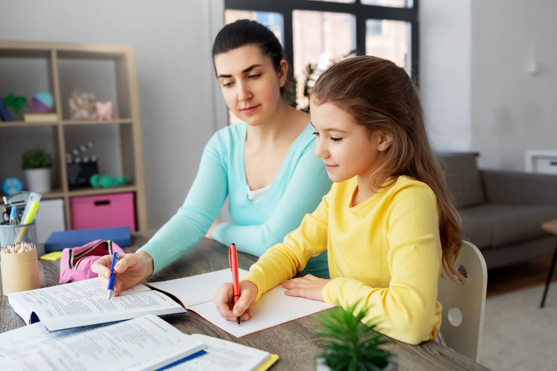 Jeune fille au pull jaune préparant ses devoirs chez elle